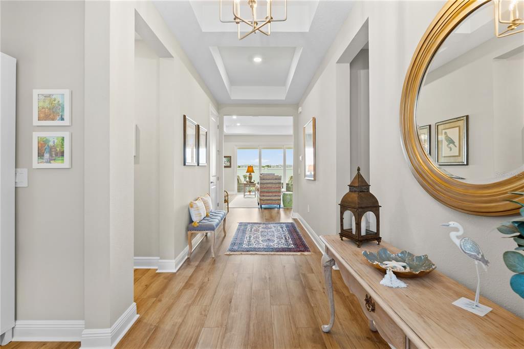 A bright hallway with wood floors leads to a living area with a water view — 1652 LUGANO CIRCLE, NOKOMIS, FL