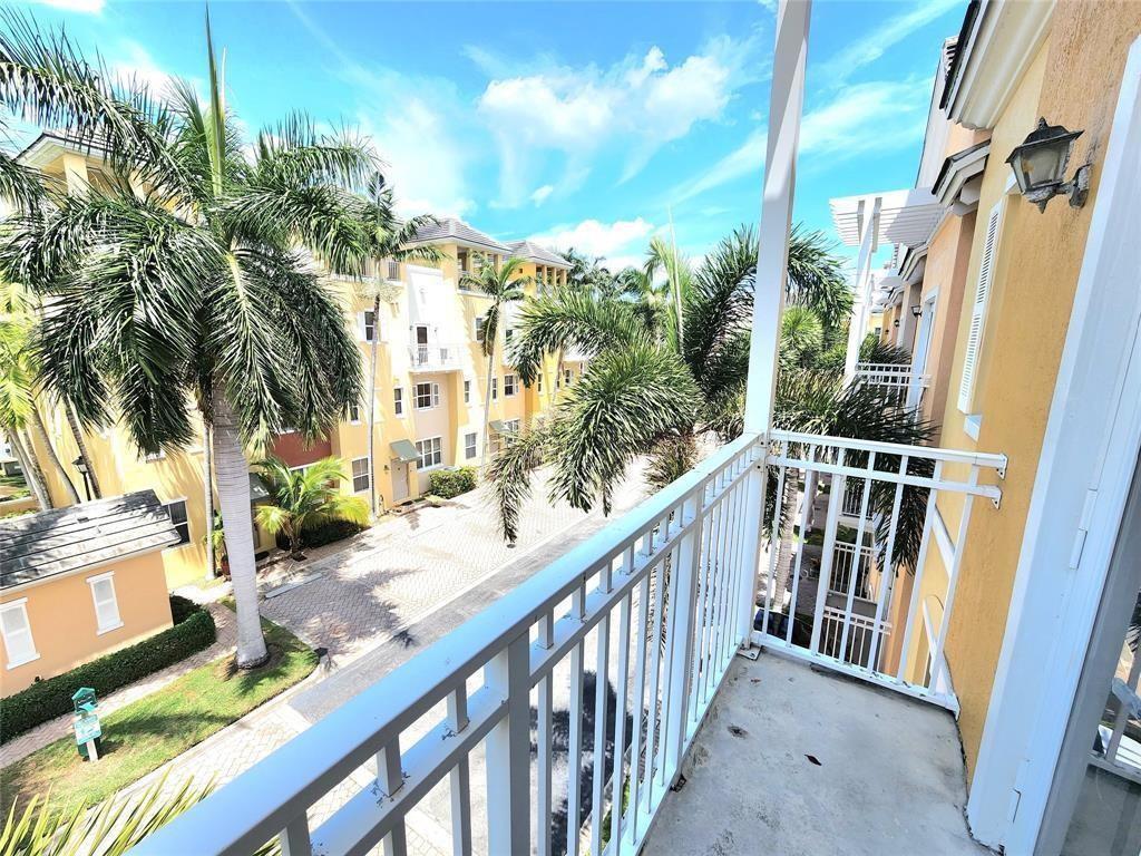 A view from a balcony overlooking a paved street, palm trees, and yellow apartment buildings — 2317 Vintage Drive, Lighthouse Point FL 33064, LIGHTHOUSE POINT, FL