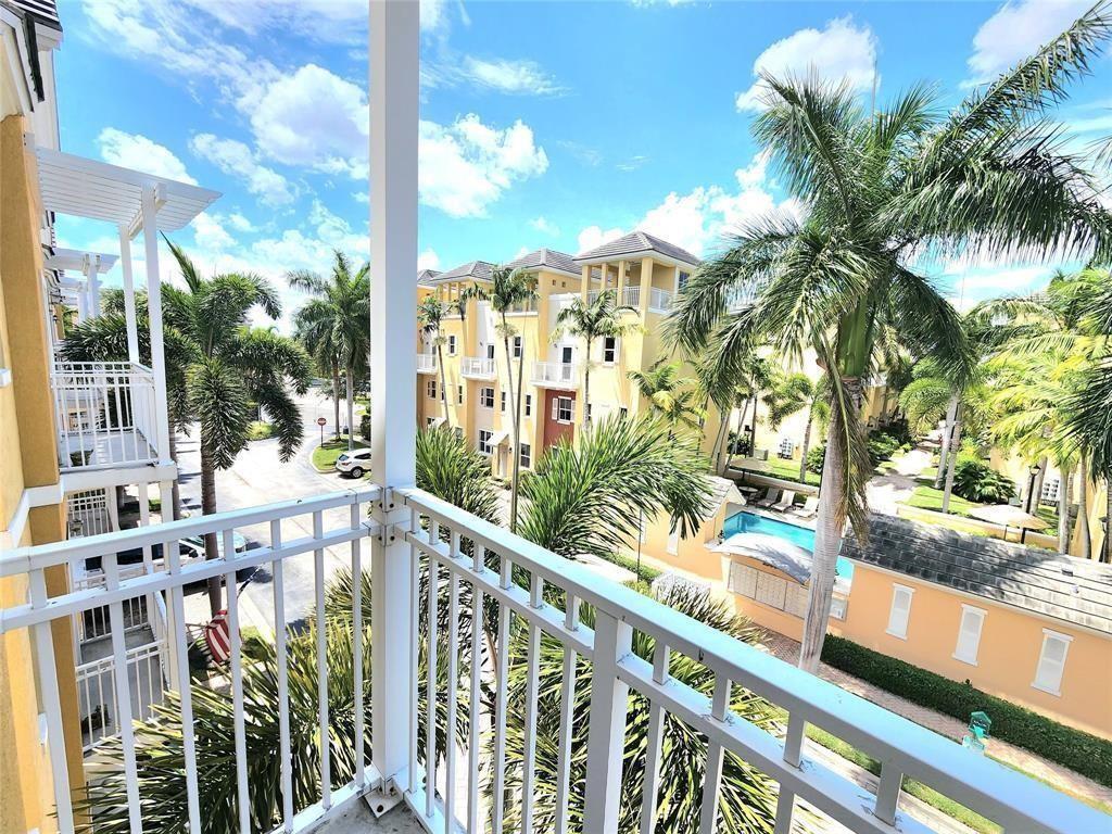 A view from a balcony overlooking a residential complex with palm trees and a pool — 2317 Vintage Drive, Lighthouse Point FL 33064, LIGHTHOUSE POINT, FL