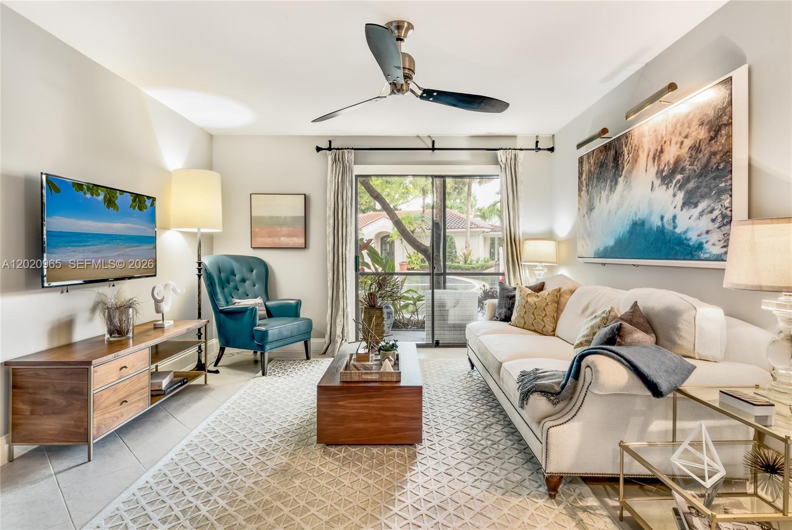 A living room features a white sofa, a teal armchair, a wooden coffee table, and television — 6503 N Military Trl, Boca Raton FL 33496, BOCA RATON, FL