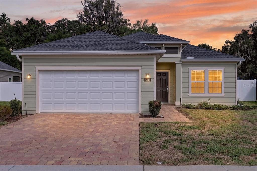 A single-story house with light green siding, a two-car garage, and a paved driveway — 1700 NW 44TH COURT ROAD, OCALA, FL