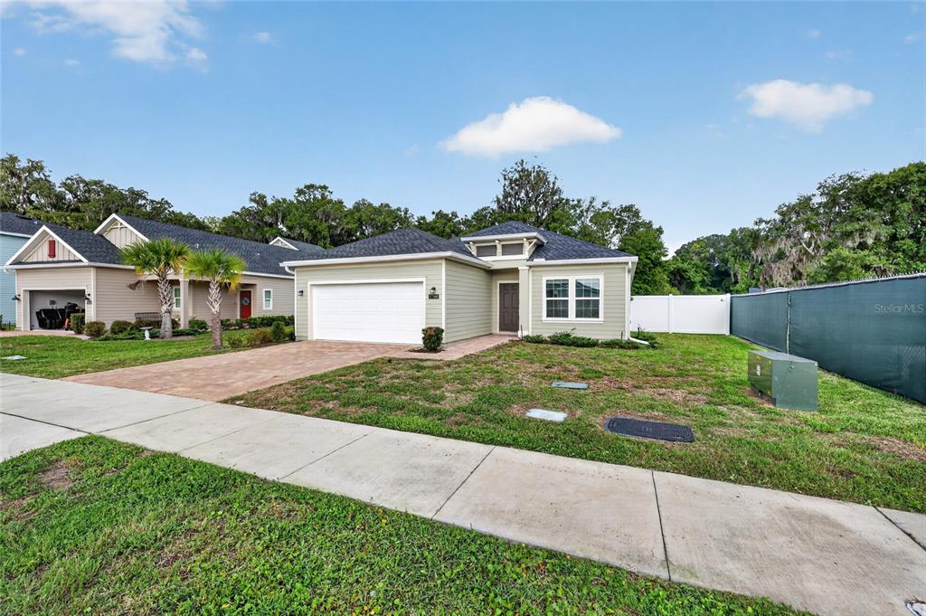 A single-story house with light green siding, a two-car garage, and a paved driveway — 1700 NW 44TH COURT ROAD, OCALA, FL