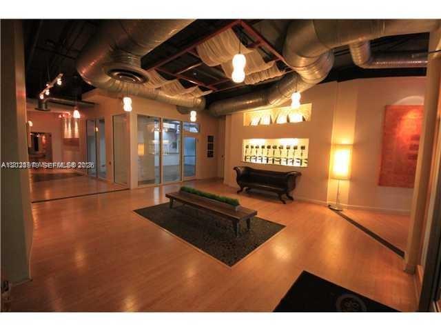 A modern lobby features wood flooring, exposed ductwork, recessed wall niches, and a wooden bench — 10 SW South River Dr # 801, Miami FL 33130, MIAMI, FL