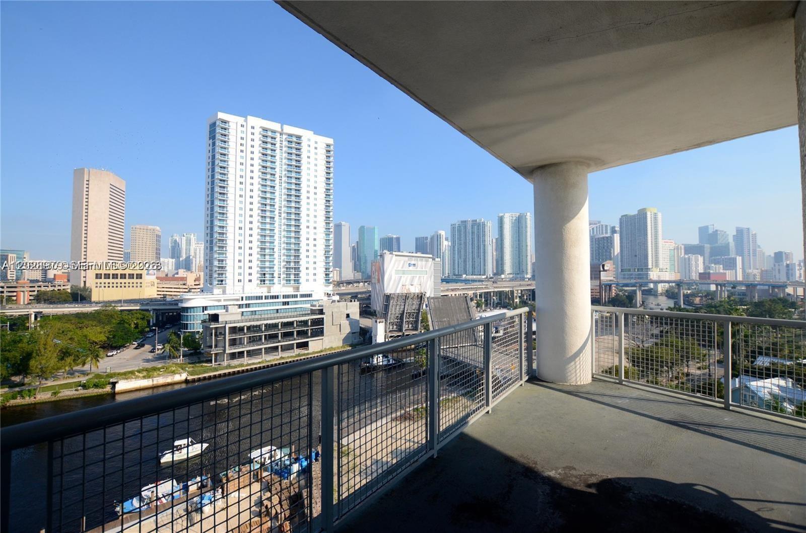 A balcony overlooks a river, a drawbridge, and a city skyline under a clear sky — 10 SW South River Dr # 801, Miami FL 33130, MIAMI, FL