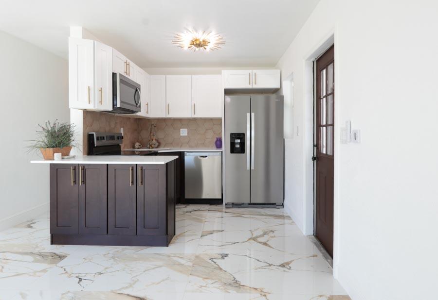 A kitchen features white upper cabinets, dark lower cabinets, stainless steel appliances, and marble flooring — 251 Avenue O, Riviera Beach FL 33404, RIVIERA BEACH, FL