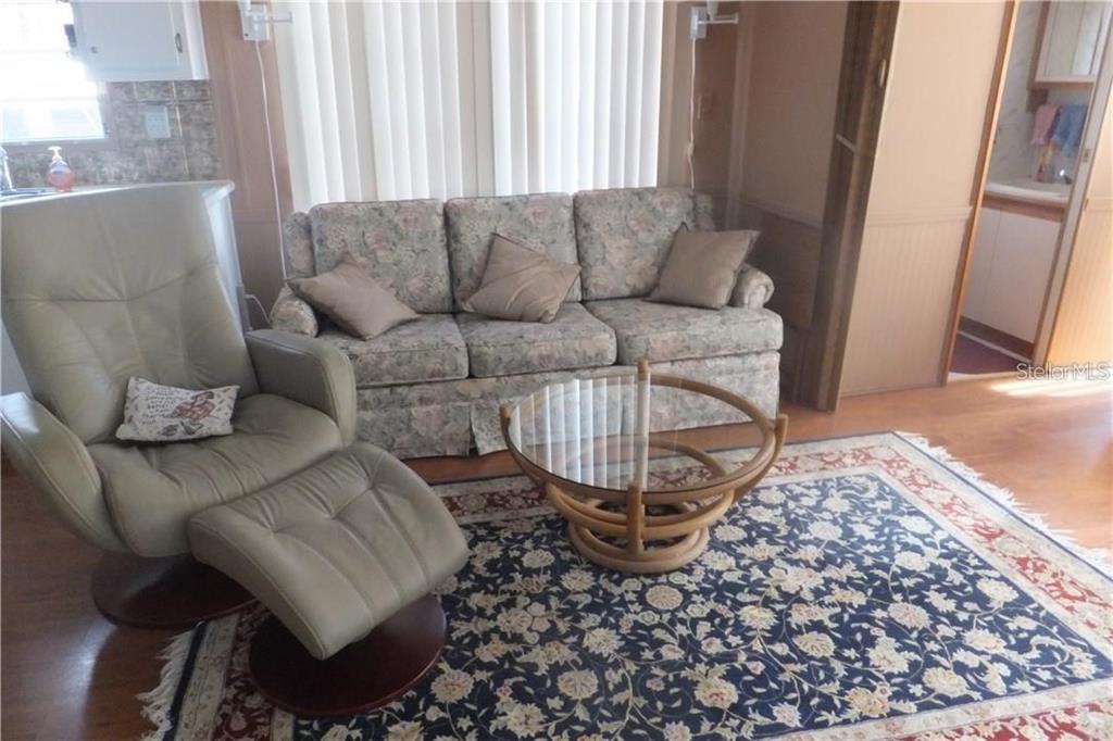 A living room features a floral sofa, a tan recliner with ottoman, and a glass-topped table — 351 CITRUS RIDGE DRIVE, DAVENPORT, FL