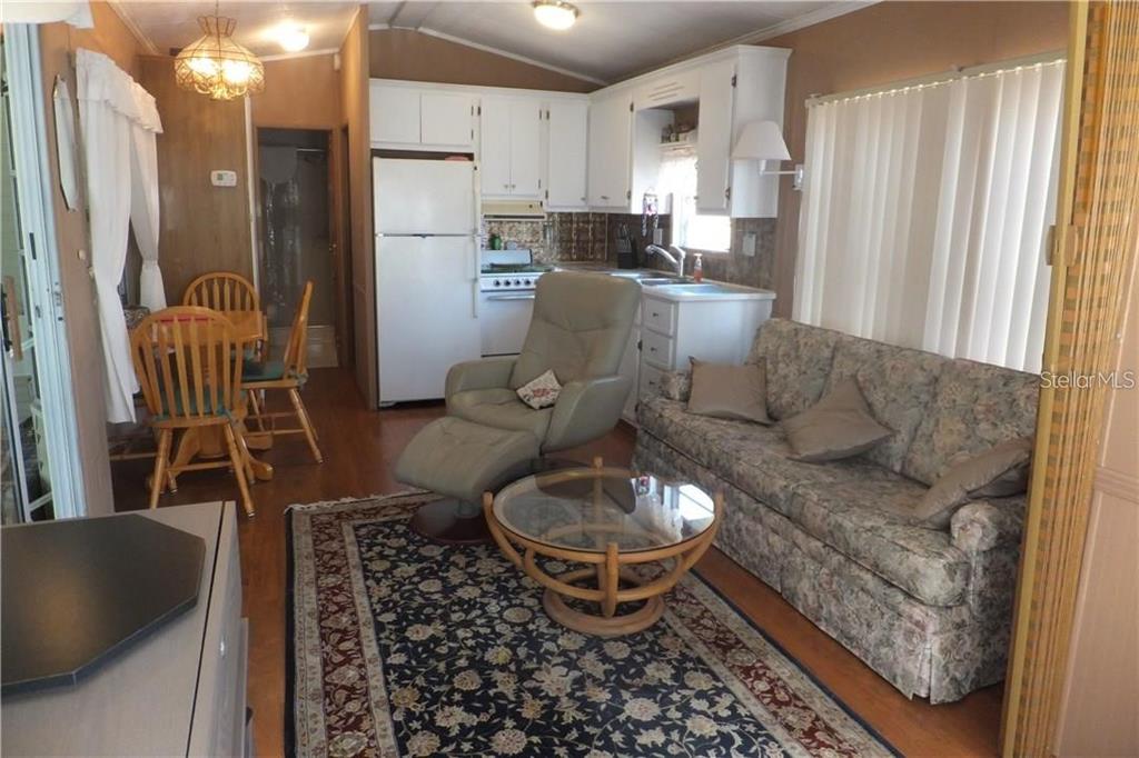 A living room and kitchen area featuring a floral sofa, recliner, and wooden dining set — 351 CITRUS RIDGE DRIVE, DAVENPORT, FL