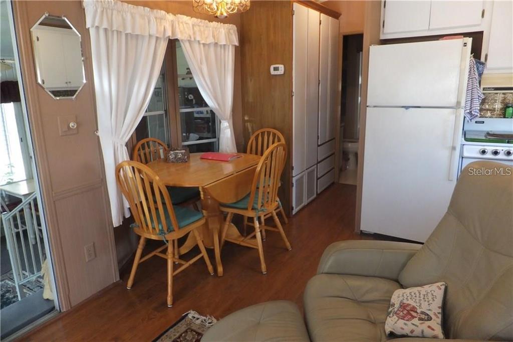 A dining area with a wooden table and chairs sits next to a white refrigerator — 351 CITRUS RIDGE DRIVE, DAVENPORT, FL