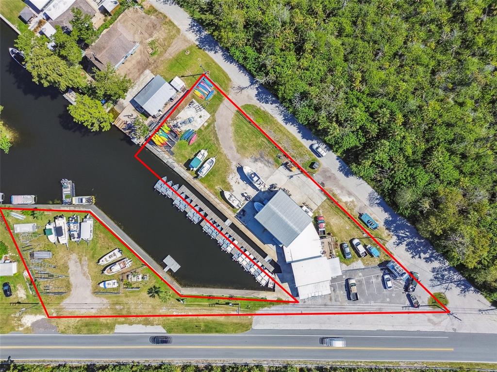 An aerial view shows a marina with boat slips, storage buildings, and parking along a canal — 7154 SHOAL LINE BOULEVARD, WEEKI WACHEE, FL