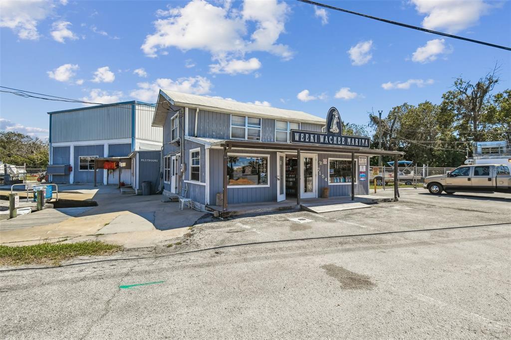 A gray, two-story marina building with a sign and a large adjacent storage warehouse — 7154 SHOAL LINE BOULEVARD, WEEKI WACHEE, FL