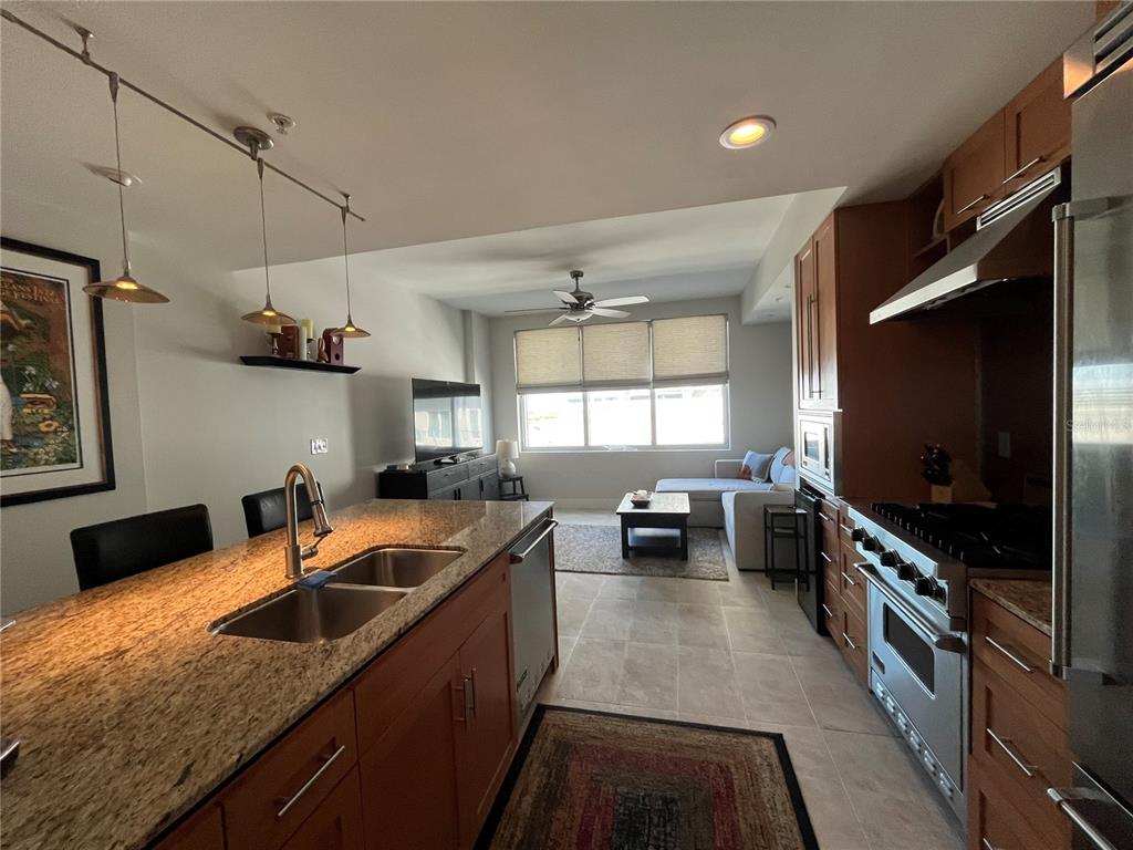 A kitchen with granite countertops and stainless steel appliances opens into a living area — 1120 E KENNEDY BOULEVARD UNIT 924, TAMPA, FL