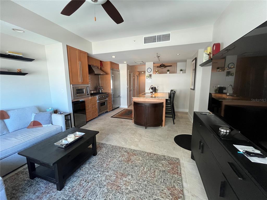 An open-concept living area features a kitchen with wood cabinets, a central island, and tile flooring — 1120 E KENNEDY BOULEVARD UNIT 924, TAMPA, FL