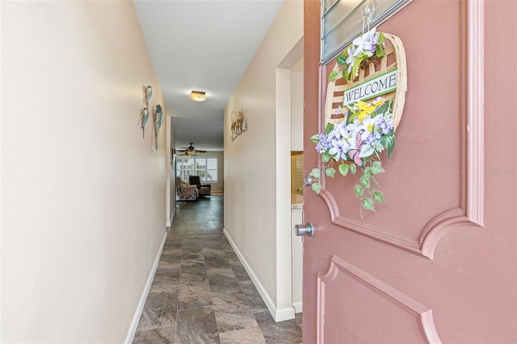 A view from an open doorway into a hallway with tiled floors and beige walls — 5521 80TH STREET N UNIT 212, ST PETERSBURG, FL