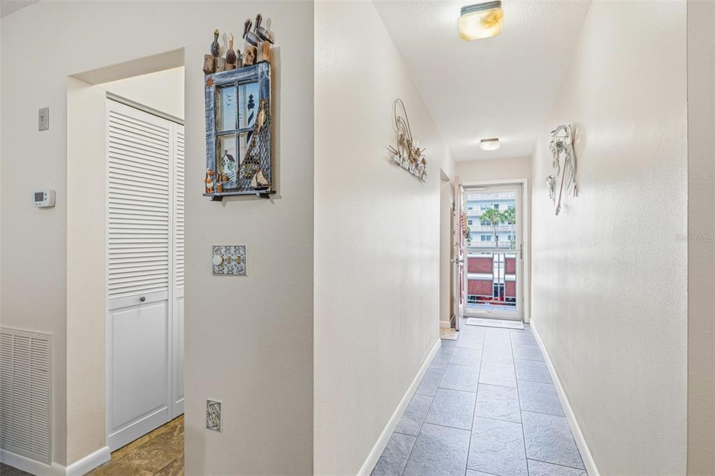A hallway with tile flooring leads to an exterior door with a view of buildings — 5521 80TH STREET N UNIT 212, ST PETERSBURG, FL