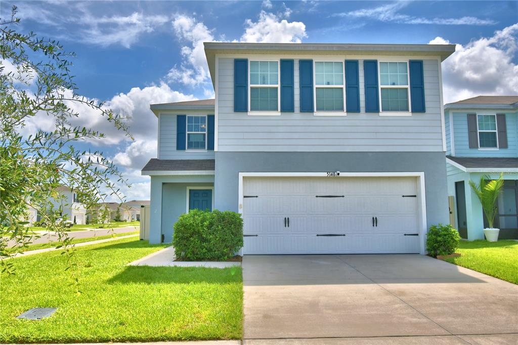 A two-story blue house with a white garage door and a green lawn — 5148 HELM STREET, HAINES CITY, FL