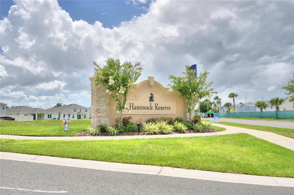 A stone and stucco monument sign for Hammock Reserve stands on a grassy corner lot — 5148 HELM STREET, HAINES CITY, FL