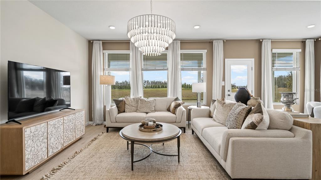 A living room features a chandelier, two sofas, a coffee table, and large windows — 4887 WALTHAM FOREST DRIVE, DAVENPORT, FL