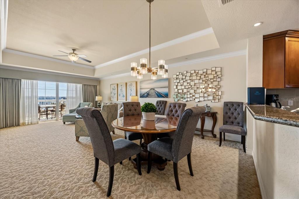 A dining area with a round table, upholstered chairs, and a chandelier near a kitchen — 1114 SUNSET VIEW CIRCLE UNIT 402, REUNION, FL