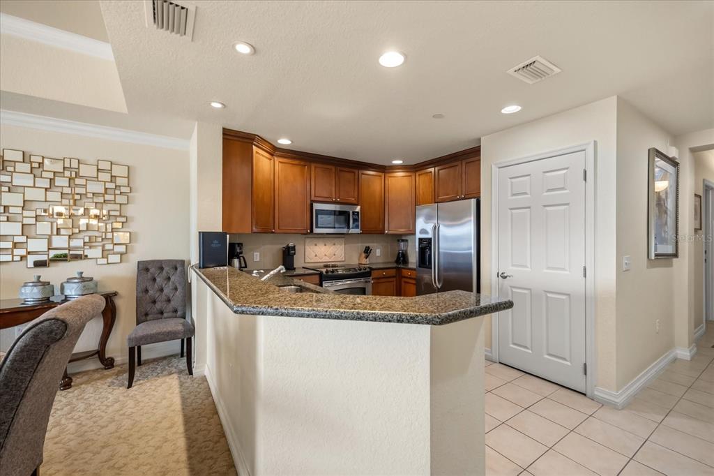 A kitchen features wood cabinets, granite countertops, stainless steel appliances, and a breakfast bar — 1114 SUNSET VIEW CIRCLE UNIT 402, REUNION, FL