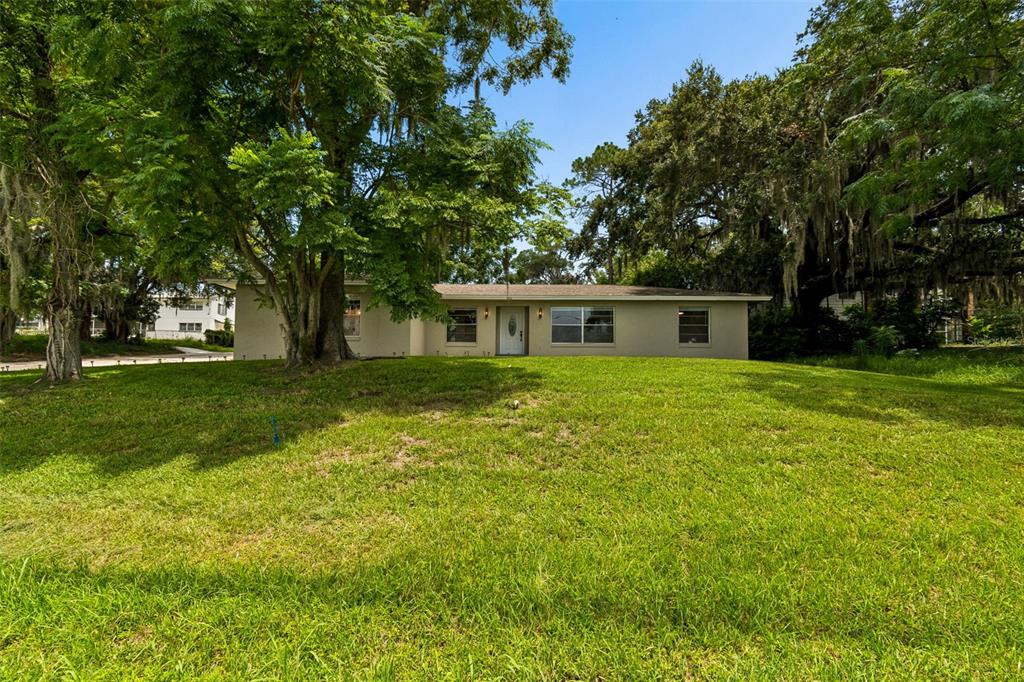 A single-story house with a light-colored exterior sits behind a large, grassy front yard — 400 E SILVER STAR ROAD, OCOEE, FL