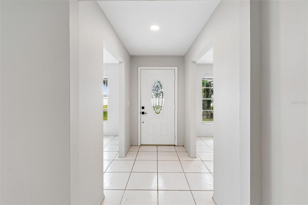 A white front door with a decorative glass insert sits at the end of a hallway — 400 E SILVER STAR ROAD, OCOEE, FL