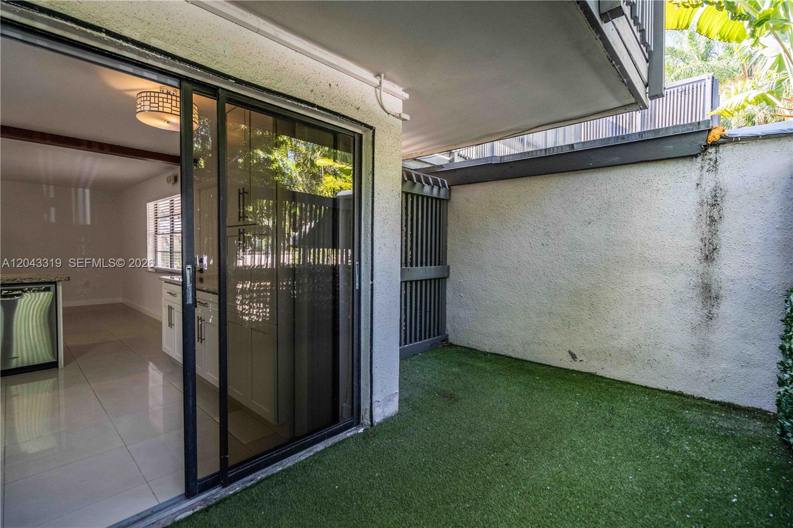 A sliding glass door opens from a tiled interior room to a small artificial turf patio — 3265 Virginia St # 1, Miami FL 33133, MIAMI, FL