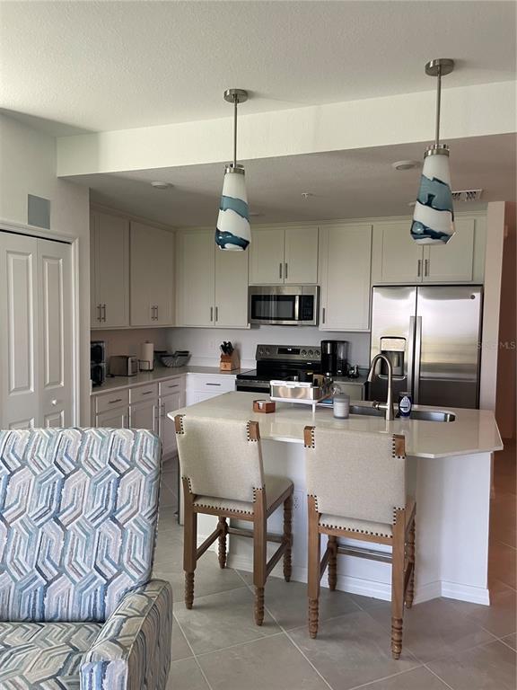 A kitchen features white cabinetry, stainless steel appliances, a quartz island, and two pendant lights — 17595 OPAL SAND DRIVE UNIT 208, VENICE, FL