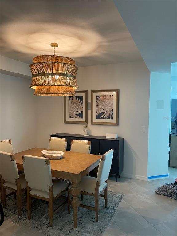 A dining room features a wooden table, upholstered chairs, a textured pendant light, and artwork — 17595 OPAL SAND DRIVE UNIT 208, VENICE, FL