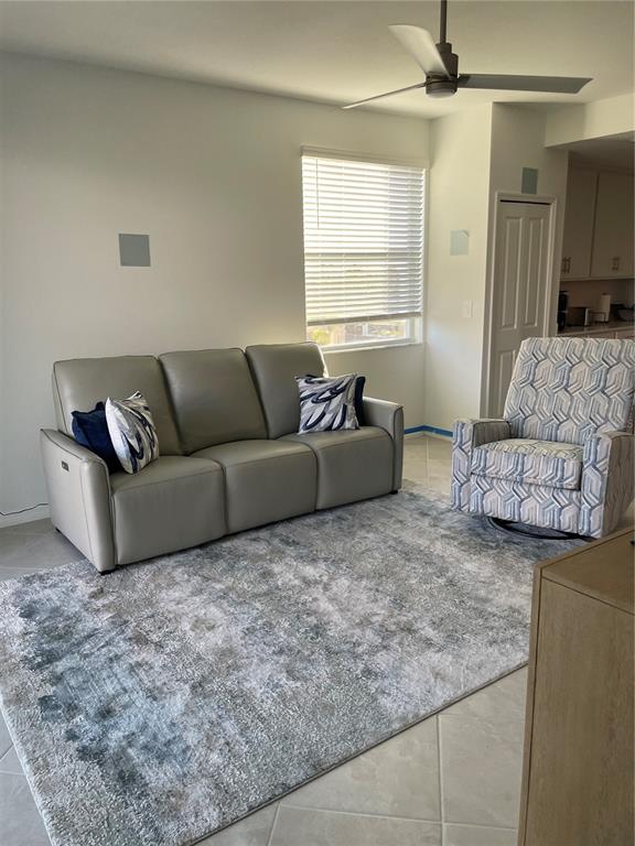 A living room features a gray leather sofa, a patterned armchair, and a large rug — 17595 OPAL SAND DRIVE UNIT 208, VENICE, FL