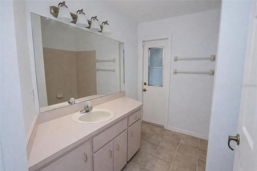 A bathroom features a vanity with a light-colored countertop, a large mirror, and tile flooring — 8276 SHORT WAY, LAKELAND, FL