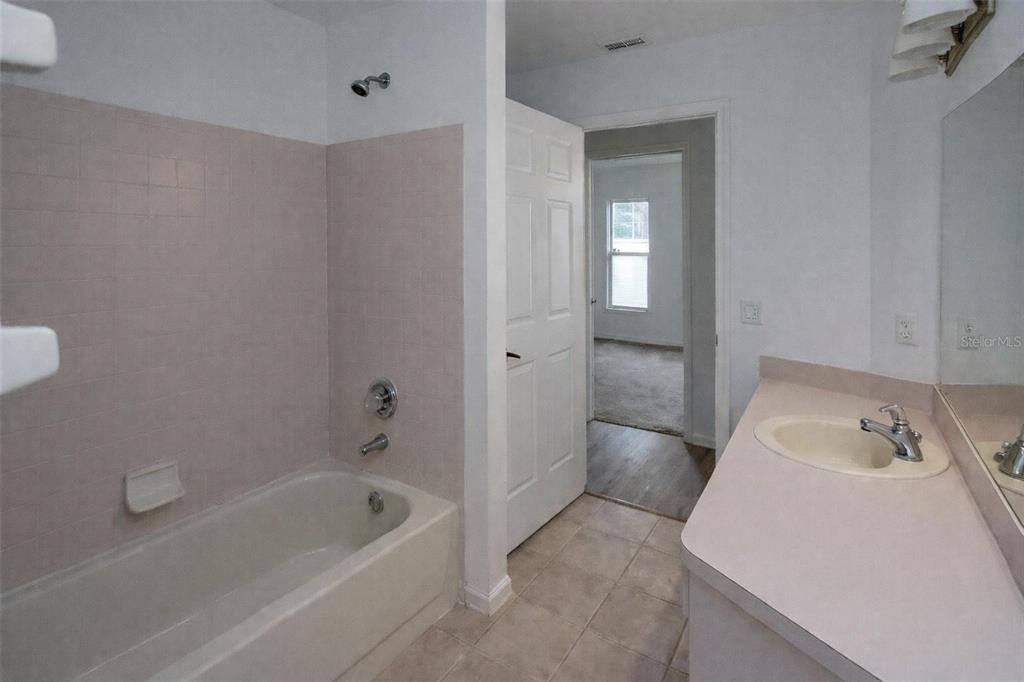 A bathroom features a beige bathtub with tile surround, a vanity, and a doorway — 8276 SHORT WAY, LAKELAND, FL