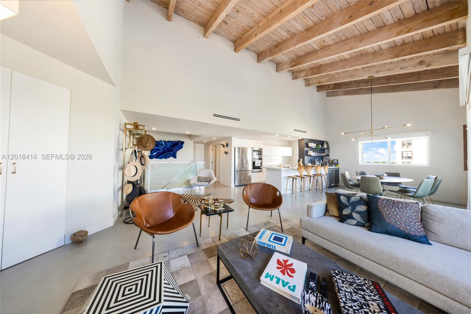 A spacious living area features vaulted wood-beamed ceilings, modern furniture, and an open-concept kitchen — 50 Ocean Lane Dr, Key Biscayne FL 33149, KEY BISCAYNE, FL