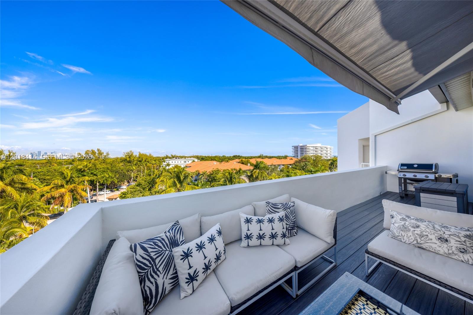 A balcony features outdoor seating, a grill, and a view of trees and buildings — 50 Ocean Lane Dr, Key Biscayne FL 33149, KEY BISCAYNE, FL