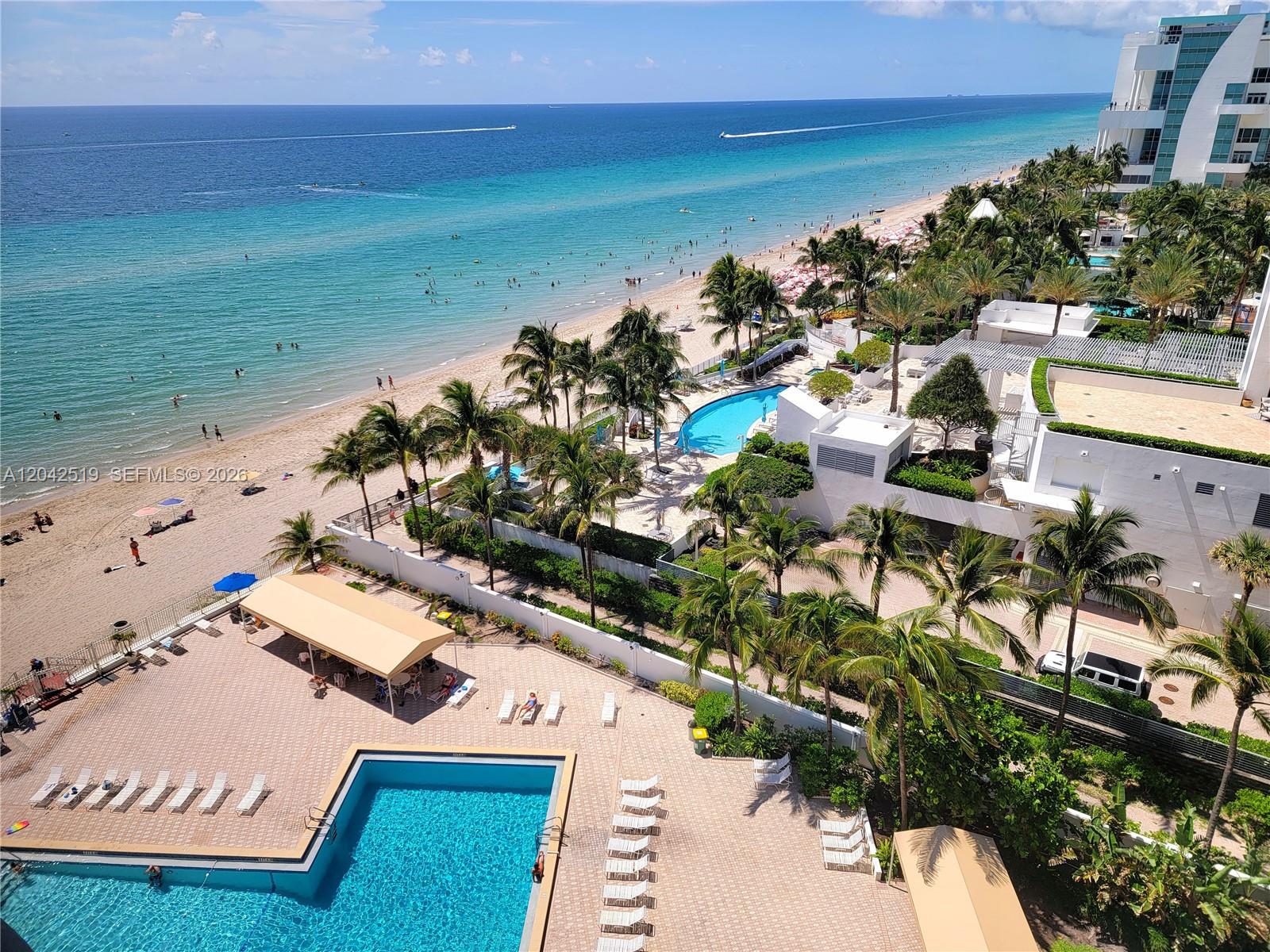 An elevated view shows a beach, two swimming pools, palm trees, and a resort building — 3505 S Ocean Dr # 412, Hollywood FL 33019, HOLLYWOOD, FL