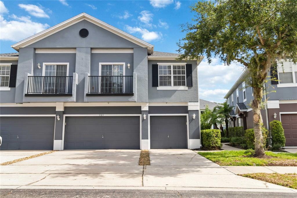 A two-story gray townhouse features a two-car garage, a balcony, and a concrete driveway — 6484 S GOLDENROD ROAD UNIT 41A, ORLANDO, FL