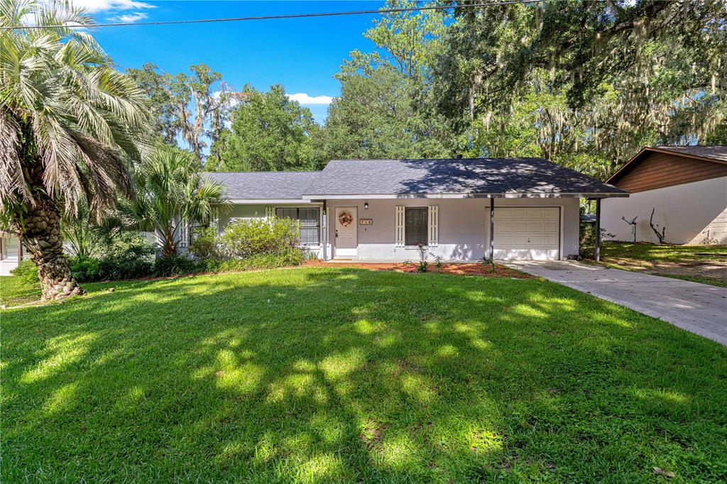 A single-story house with a white exterior, a gray roof, and an attached garage — 716 SE 31ST AVENUE, OCALA, FL
