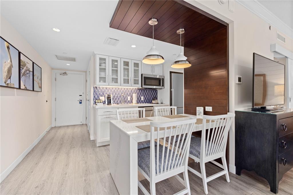 A dining area with white chairs sits before a kitchen featuring blue patterned tile backsplashes — 240 SANDS POINT ROAD UNIT 4102, LONGBOAT KEY, FL