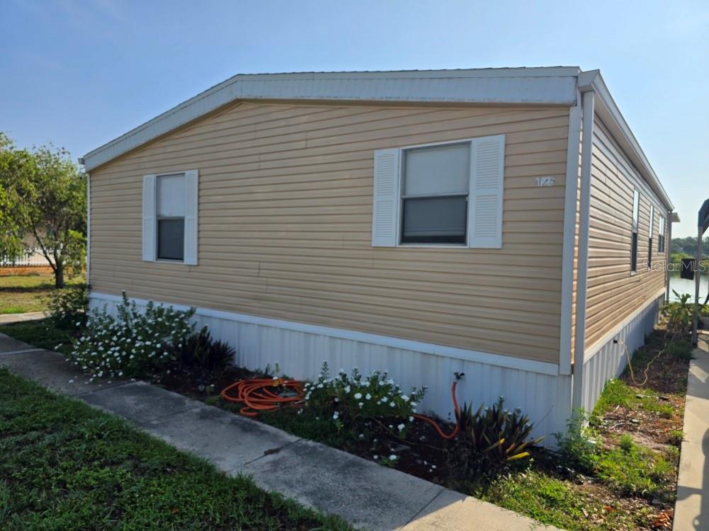 A tan, single-story manufactured home with white shutters and a white skirting foundation — 1125 PENINSULAR DRIVE, LAKE WALES, FL