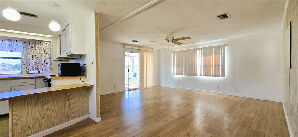 A kitchen with a wood-paneled breakfast bar opens into a living area with wood flooring — 1125 PENINSULAR DRIVE, LAKE WALES, FL
