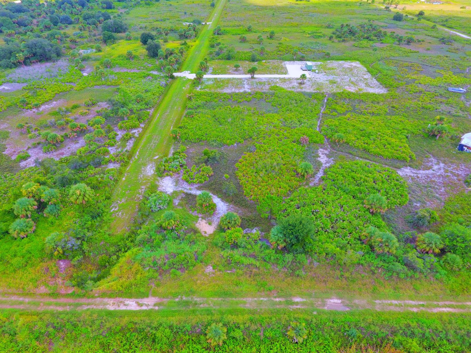 An aerial view of a rural lot featuring a cleared building pad and dirt paths — 21594 NW 282nd Street, Okeechobee FL 34972, OKEECHOBEE, FL