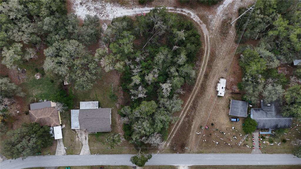 An aerial view shows two houses separated by a wooded lot along a paved road — 7800 E SAVANNAH DRIVE, FLORAL CITY, FL