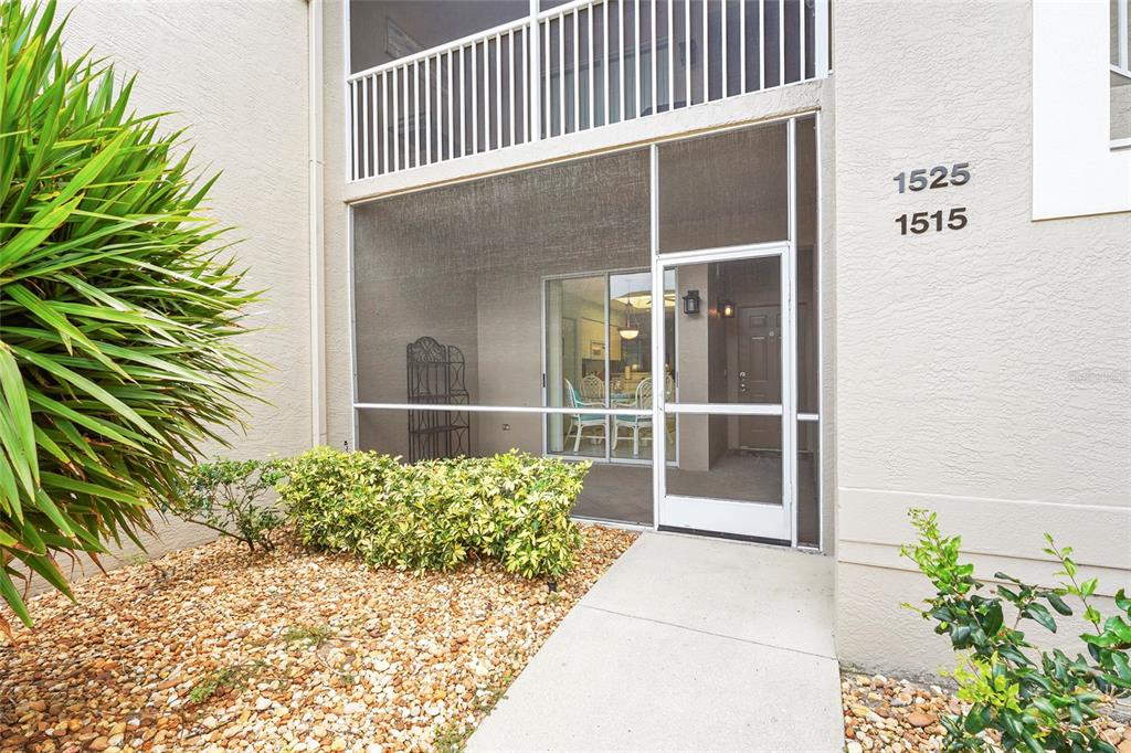 A concrete walkway leads to a screened-in patio entrance with a white door — 9550 HIGH GATE DRIVE UNIT 1515, SARASOTA, FL
