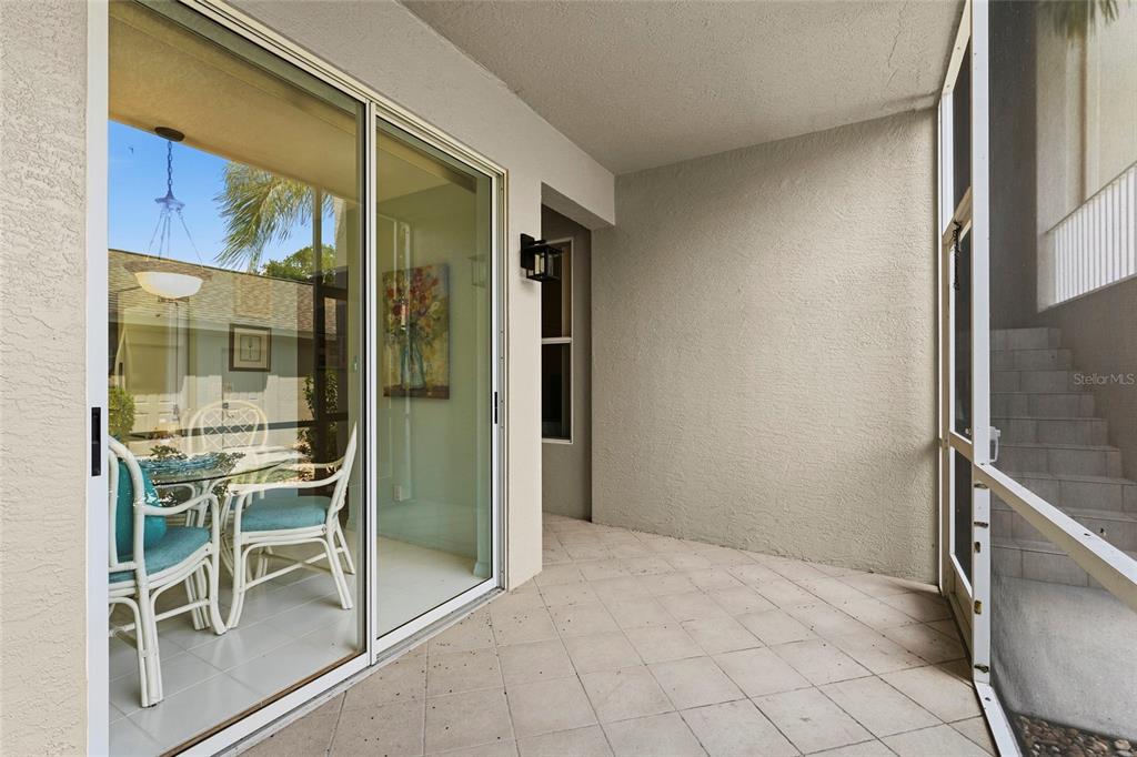 A covered patio features tiled flooring, a sliding glass door, and a screened-in wall — 9550 HIGH GATE DRIVE UNIT 1515, SARASOTA, FL