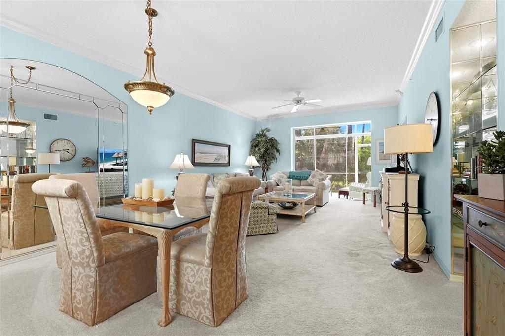 A living and dining room with light blue walls, beige carpet, and a glass-topped table — 9550 HIGH GATE DRIVE UNIT 1515, SARASOTA, FL