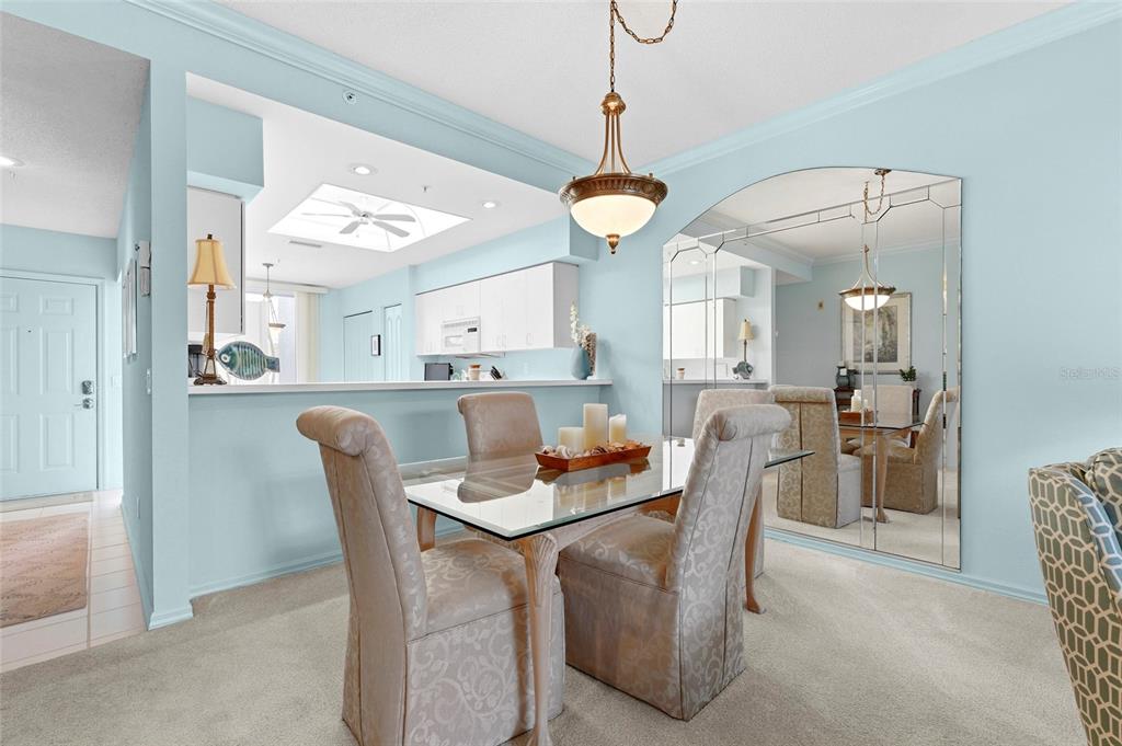 A dining area with a glass table, upholstered chairs, and a large wall mirror — 9550 HIGH GATE DRIVE UNIT 1515, SARASOTA, FL