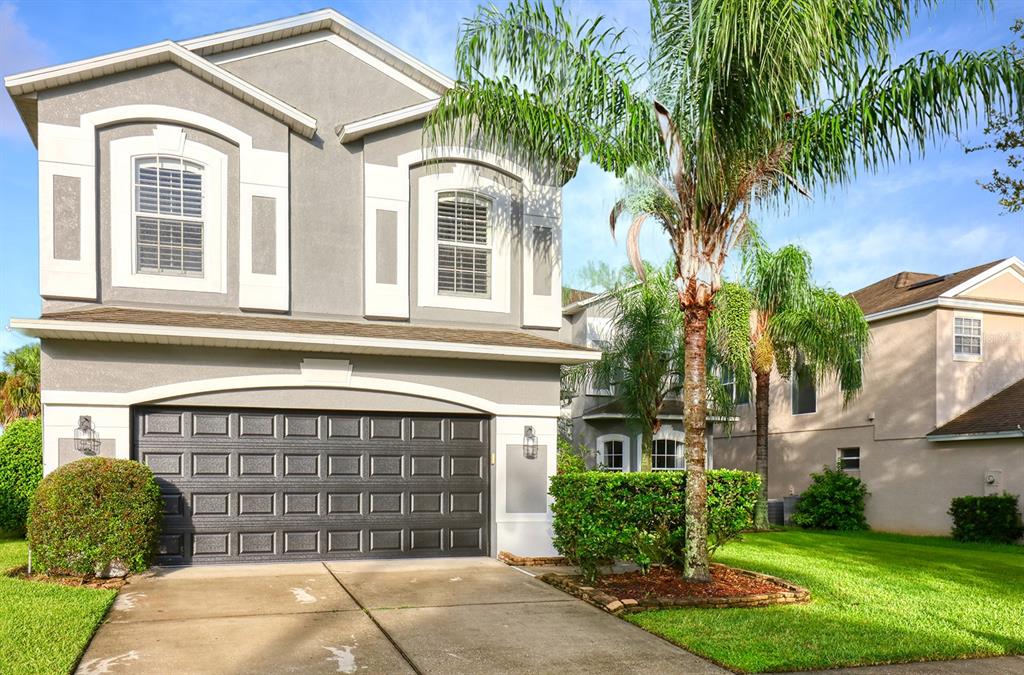 A two-story house with a gray stucco exterior, a two-car garage, and a palm tree — 13412 FOX GLOVE STREET, WINTER GARDEN, FL