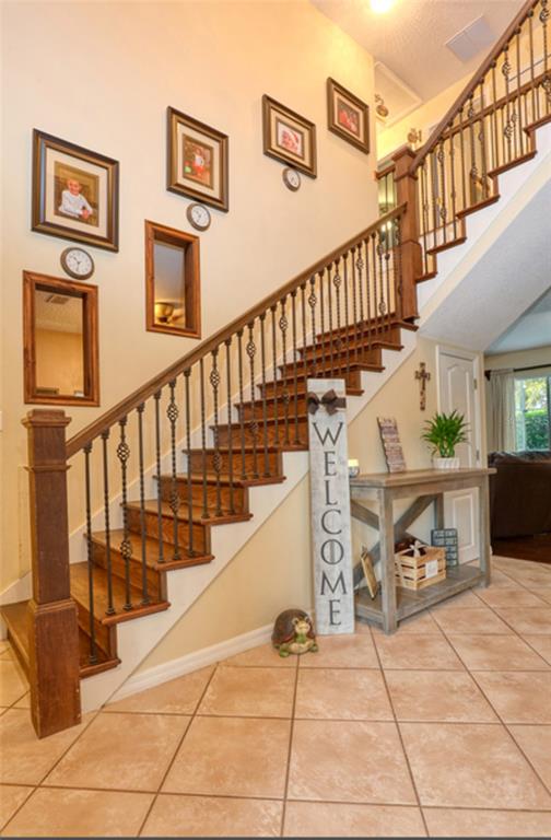 A staircase with wooden treads and metal railings stands in a tiled entryway — 13412 FOX GLOVE STREET, WINTER GARDEN, FL