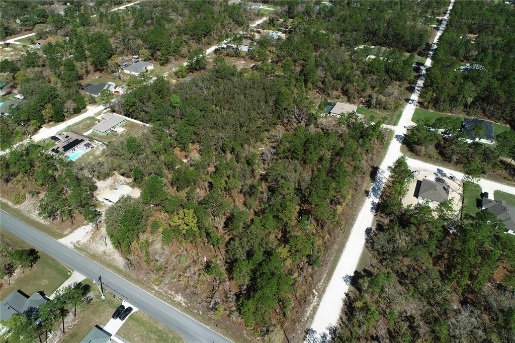 An aerial view shows a wooded, undeveloped residential lot situated between two paved roads — 17419 MALIBAR ROAD, WEEKI WACHEE, FL