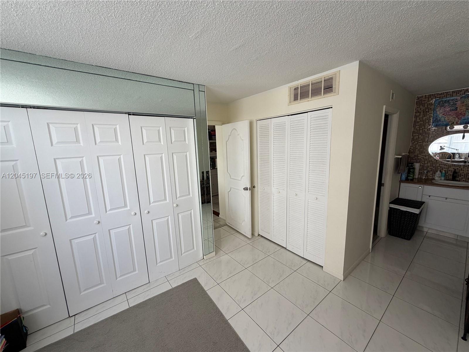 A room features white tiled floors, multiple closet doors, and an adjacent bathroom vanity area — 1849 S Ocean Dr # 508, Hallandale Beach FL 33009, HALLANDALE BEACH, FL