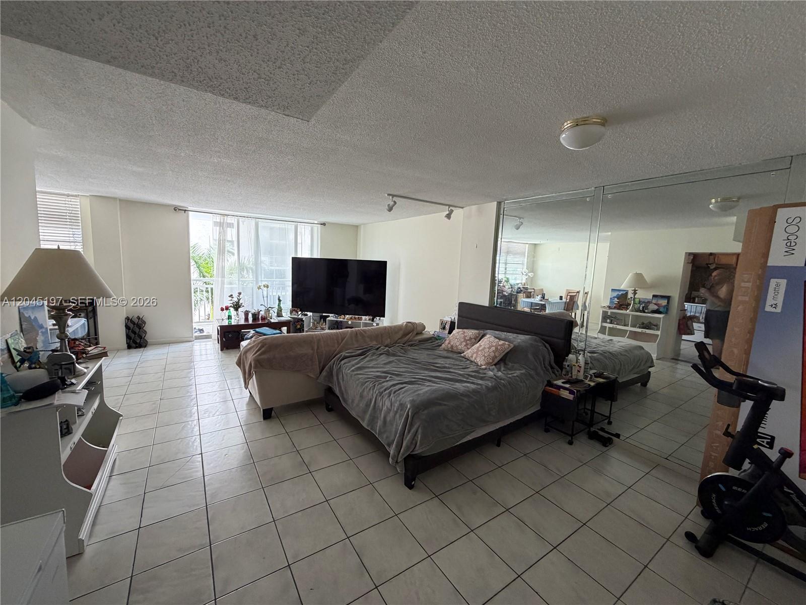 A bedroom features tiled floors, a large bed, a television, and mirrored closet doors — 1849 S Ocean Dr # 508, Hallandale Beach FL 33009, HALLANDALE BEACH, FL